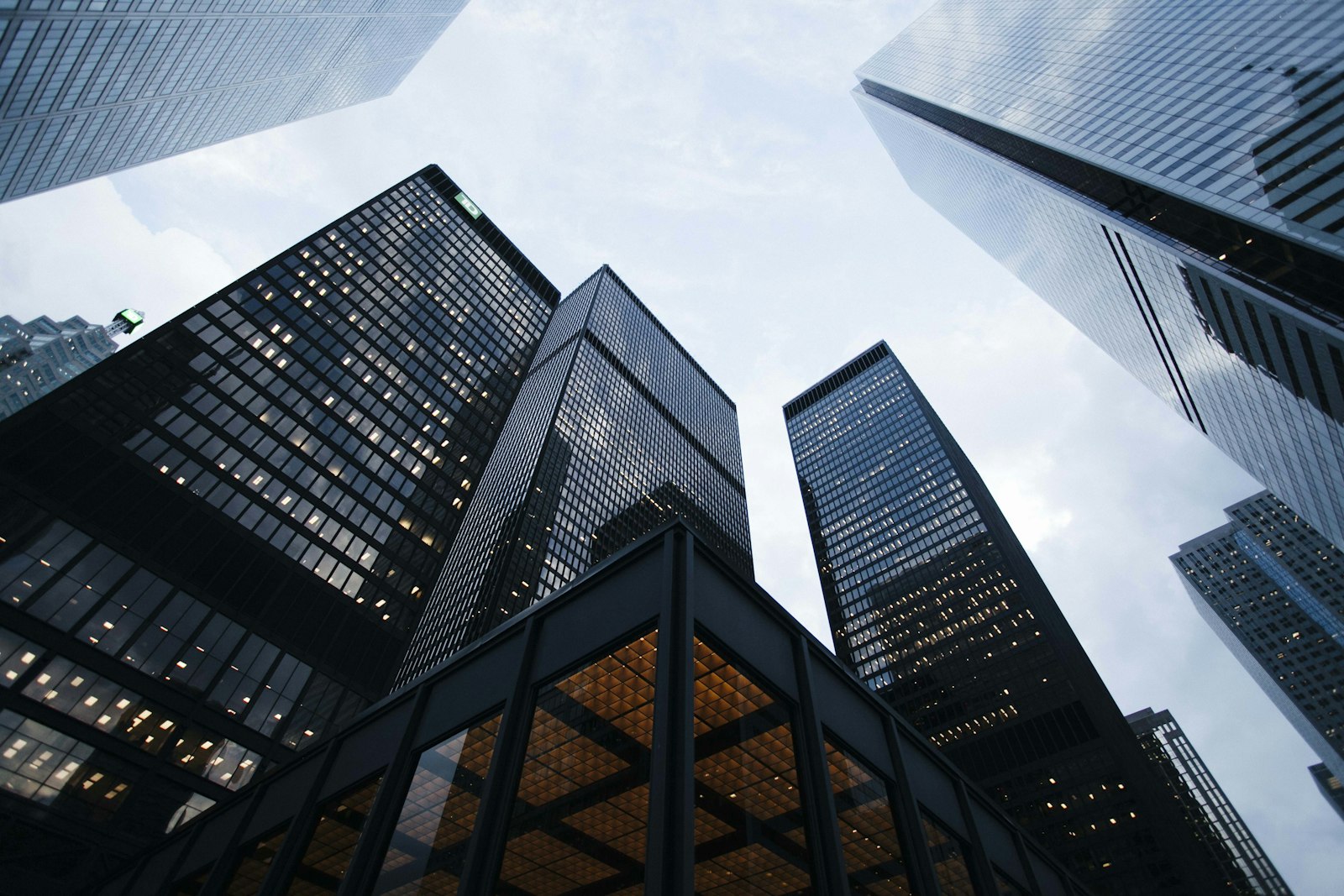 Downtown office towers seen from below against a soft blue sky.